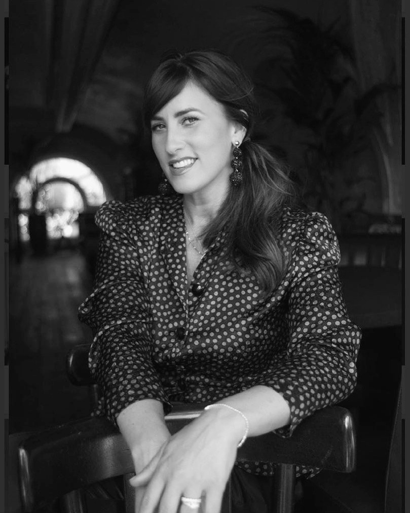 Lucinda Belle seated and smiling, in a patterned blouse
